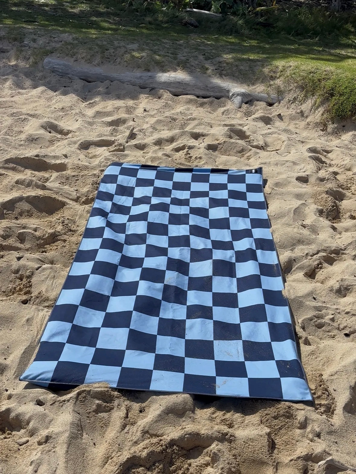 Checkered towel on sandy ground with natural background