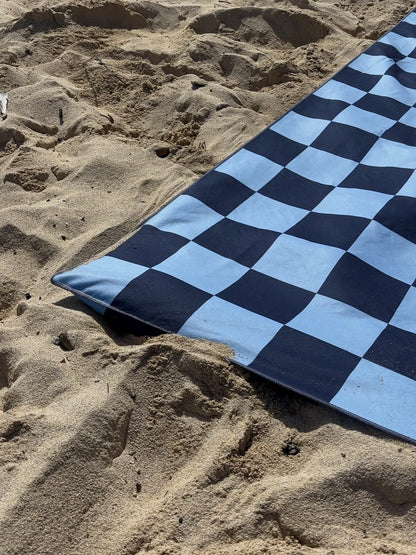 Blue and black checkered towel on sandy ground